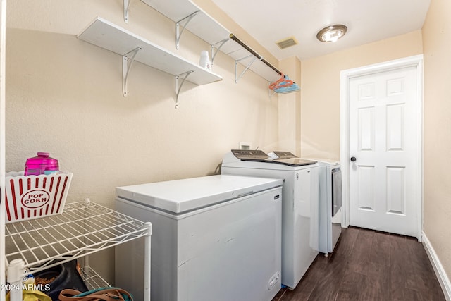 clothes washing area featuring dark wood-type flooring and washer and dryer