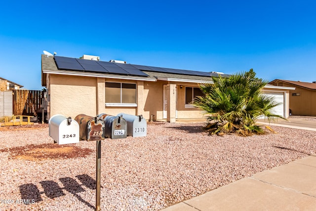 ranch-style home featuring solar panels and a garage