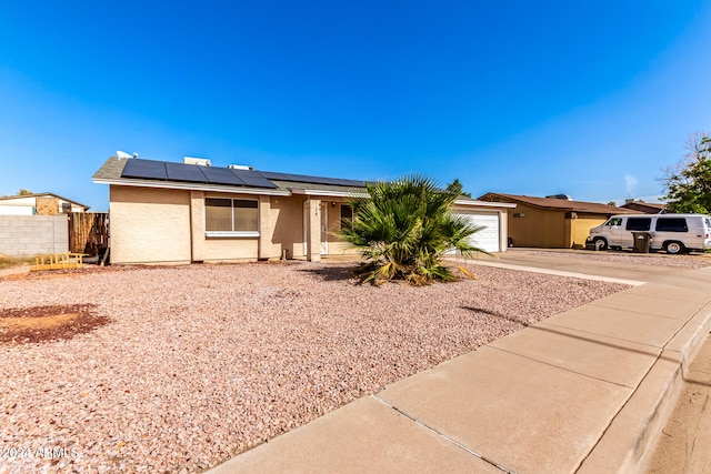 single story home with solar panels and a garage