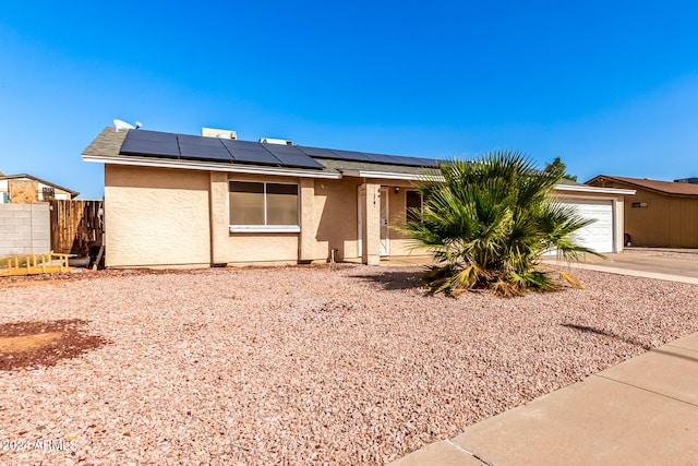 single story home featuring a garage and solar panels