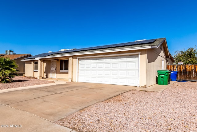 ranch-style home with a garage and solar panels