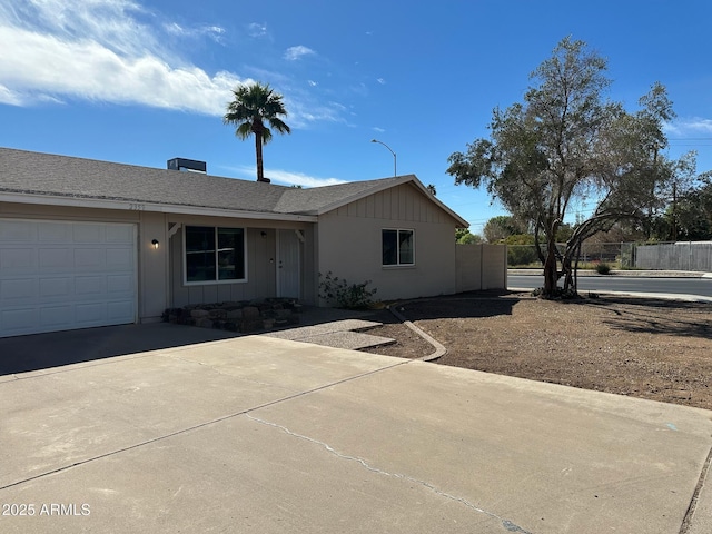 single story home with roof with shingles, an attached garage, board and batten siding, fence, and driveway