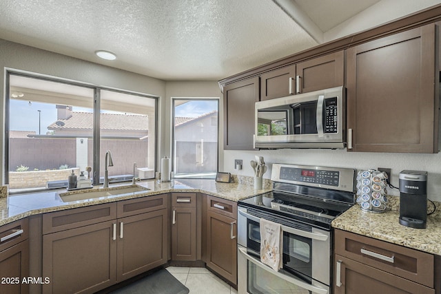 1461 W Tara Dr, Gilbert, AZ 85233 - kitchen with appliances with stainless steel finishes, a sink, light stone counters, a textured ceiling, and light tile patterned floors