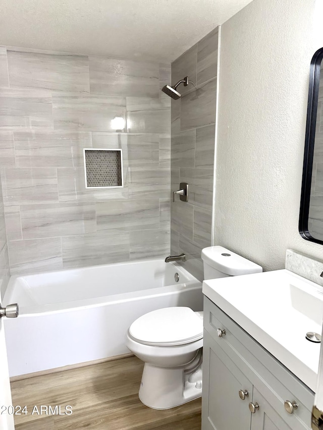 full bathroom with hardwood / wood-style flooring, tiled shower / bath, vanity, and toilet