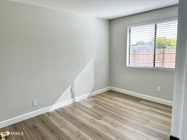 empty room featuring a textured ceiling and light wood-type flooring