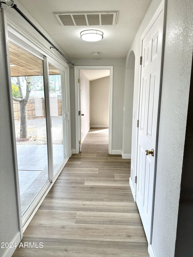 hall featuring a textured ceiling and light wood-type flooring