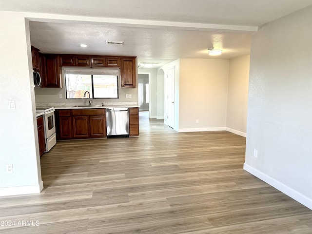 kitchen with stainless steel appliances, sink, light hardwood / wood-style flooring, and a textured ceiling