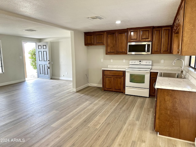 kitchen with sink, a textured ceiling, light hardwood / wood-style floors, and white range with electric cooktop