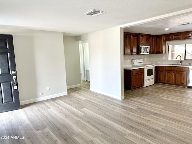 kitchen with stainless steel appliances, sink, light hardwood / wood-style flooring, and a textured ceiling