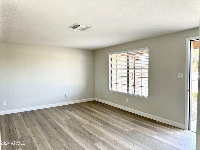 spare room with a textured ceiling and light wood-type flooring