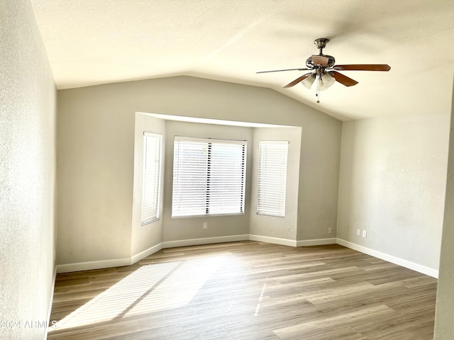 empty room featuring vaulted ceiling, ceiling fan, a textured ceiling, and light hardwood / wood-style flooring