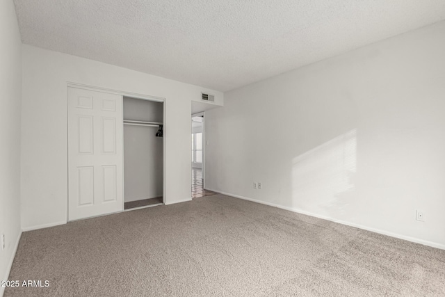 unfurnished bedroom with carpet floors, a textured ceiling, and a closet