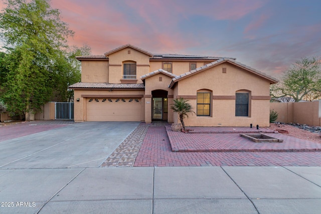 mediterranean / spanish-style home with concrete driveway, a tile roof, fence, and stucco siding