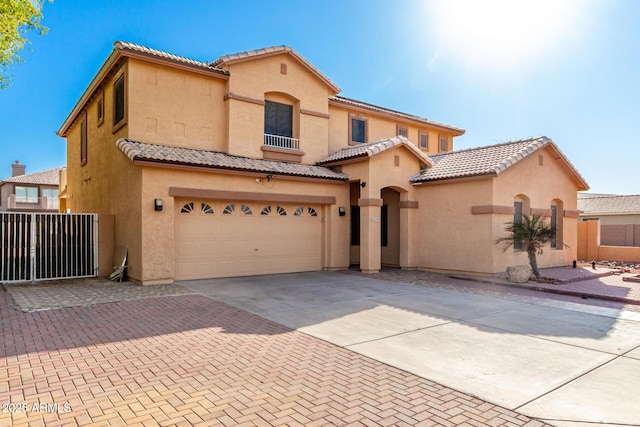 mediterranean / spanish-style home featuring a garage, stucco siding, a tiled roof, and decorative driveway