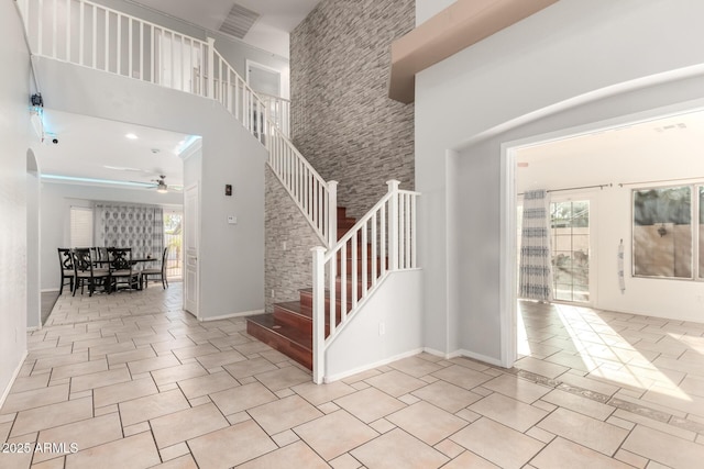 stairs featuring tile patterned floors, a high ceiling, and ceiling fan