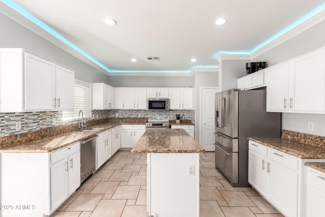 kitchen with a sink, white cabinetry, a kitchen island, and stainless steel appliances