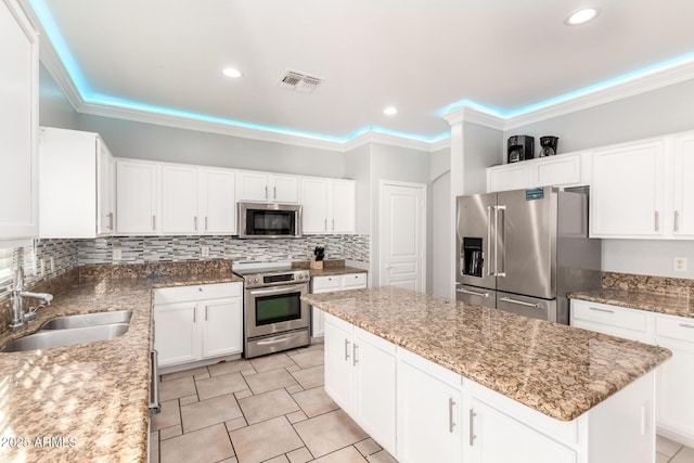 kitchen with visible vents, a kitchen island, a sink, stainless steel appliances, and backsplash