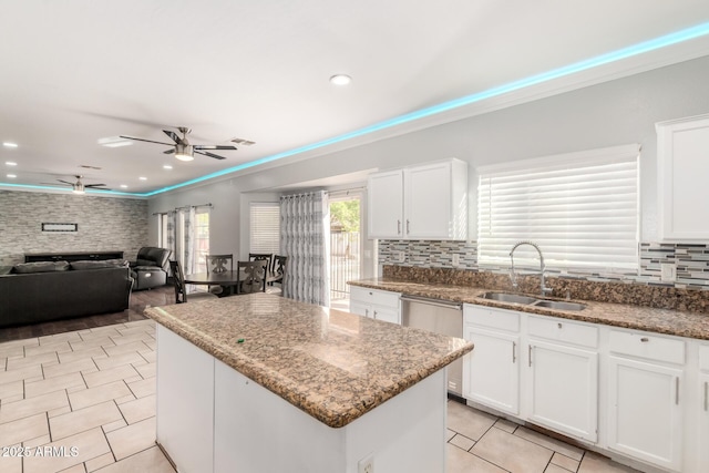 kitchen with light tile patterned floors, a center island, a ceiling fan, crown molding, and a sink