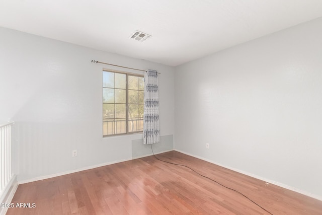 unfurnished room with visible vents, baseboards, and wood finished floors