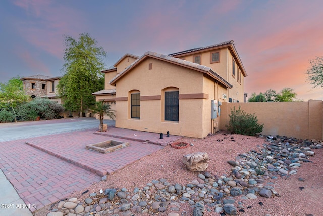 mediterranean / spanish-style house featuring a patio area, a tile roof, fence, and stucco siding