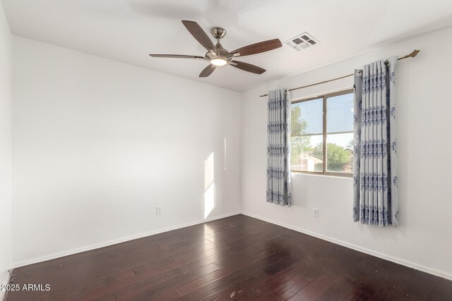 unfurnished room with dark wood-type flooring, visible vents, and baseboards