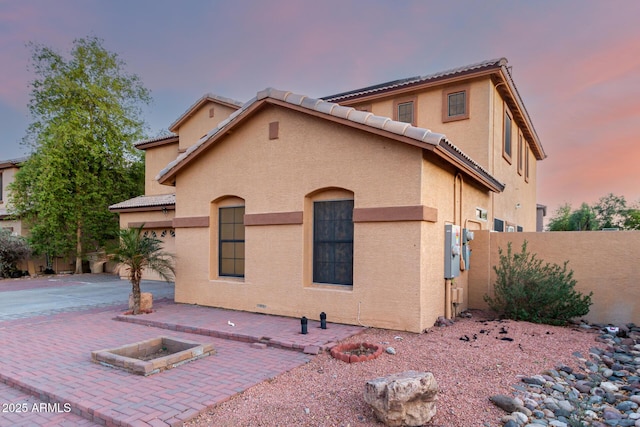view of front facade with fence, a patio, and stucco siding