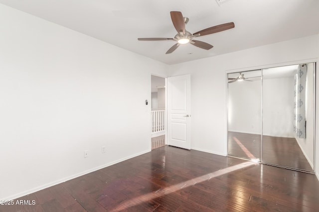 unfurnished bedroom with a closet, hardwood / wood-style flooring, baseboards, and ceiling fan