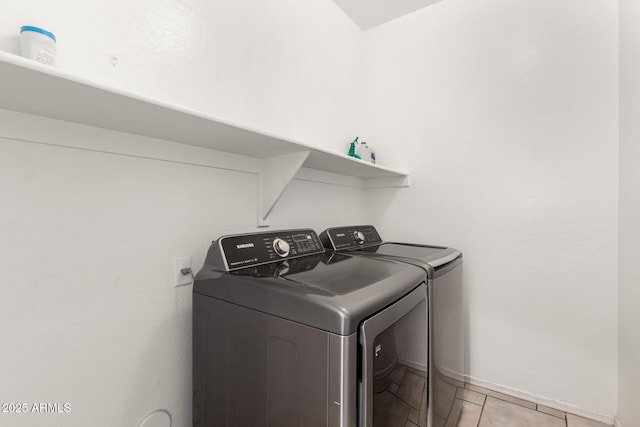 laundry area with light tile patterned floors, baseboards, washing machine and dryer, and laundry area