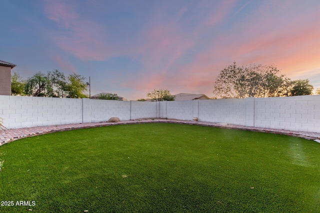 yard at dusk featuring a fenced backyard