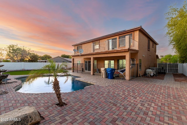 pool at dusk with a fenced backyard, a gate, a fenced in pool, and a patio