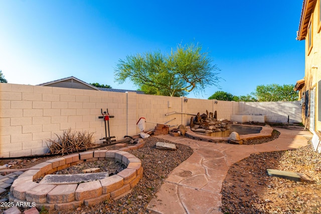 view of yard with a fenced backyard and a fire pit