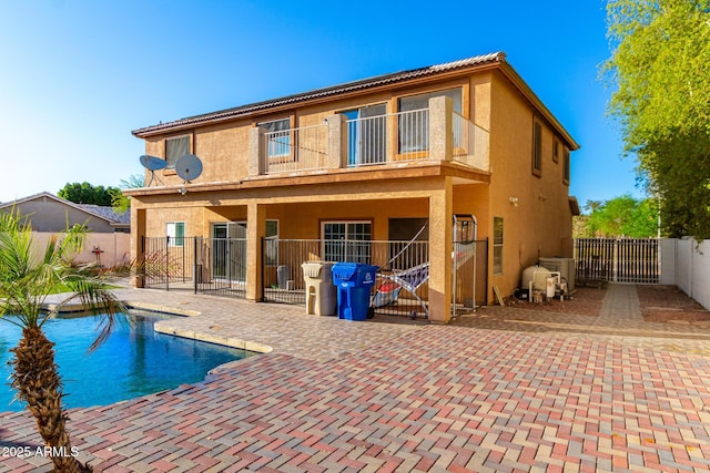 rear view of property featuring a fenced backyard, a patio, stucco siding, a fenced in pool, and a gate
