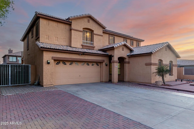 mediterranean / spanish-style house featuring concrete driveway, stucco siding, an attached garage, and a tile roof