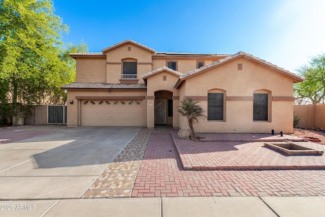 mediterranean / spanish-style home featuring a garage, a tile roof, fence, stucco siding, and driveway