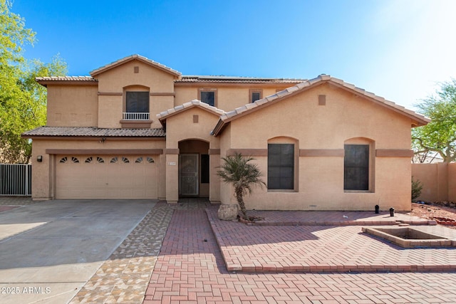 mediterranean / spanish-style house featuring a garage, stucco siding, fence, a tile roof, and concrete driveway