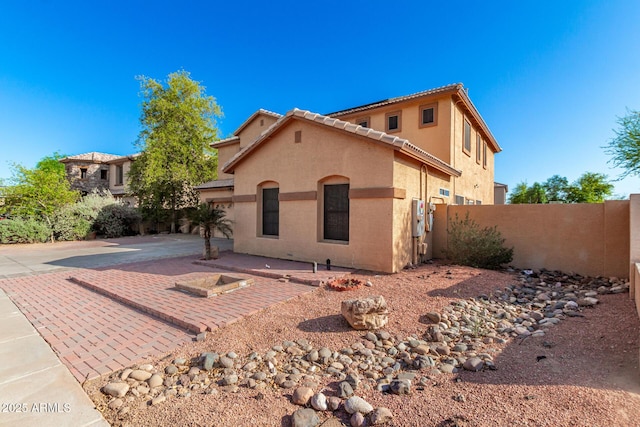 mediterranean / spanish-style house with a patio area, a tiled roof, fence, stucco siding, and driveway