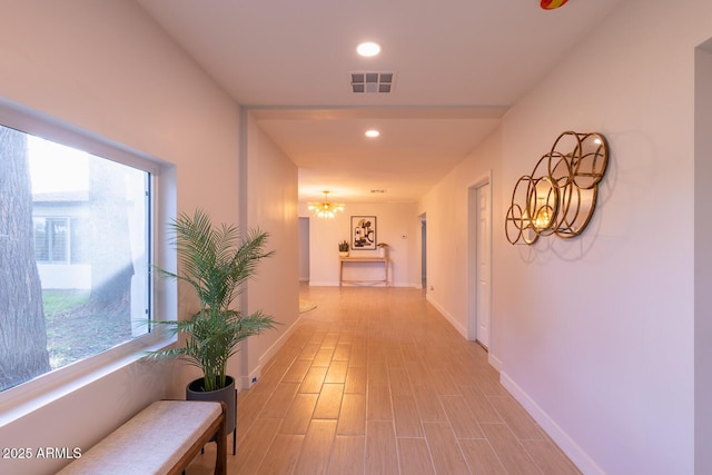 corridor with a chandelier and light hardwood / wood-style floors