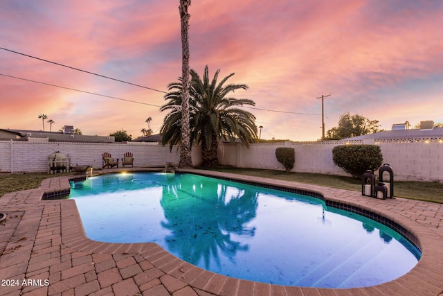 pool at dusk with a patio area