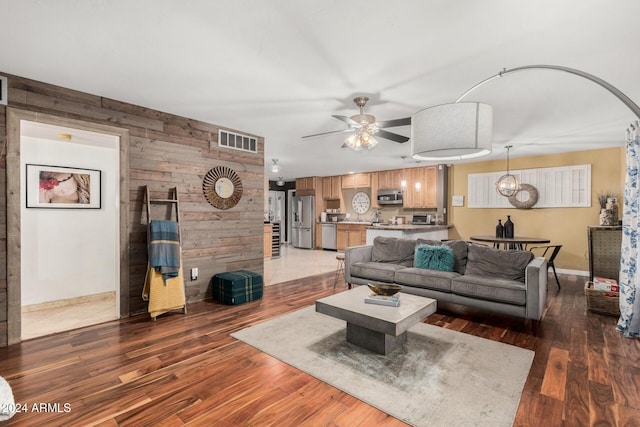 living room featuring wooden walls, ceiling fan, and dark hardwood / wood-style floors