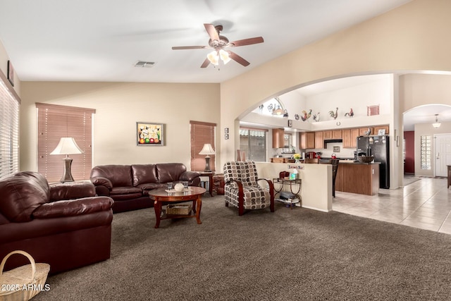 15994 W Bartlett Ave, Goodyear, AZ 85338 - living room featuring high vaulted ceiling, arched walkways, a ceiling fan, visible vents, and light carpet