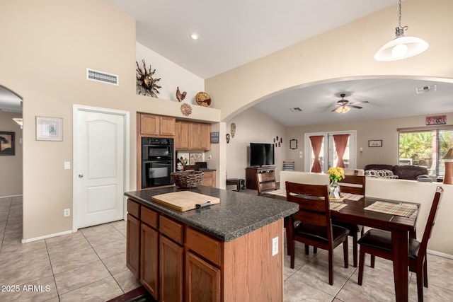 15994 W Bartlett Ave, Goodyear, AZ 85338 - kitchen with visible vents, open floor plan, dark countertops, and arched walkways