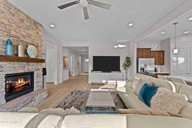 living room with a brick fireplace, ceiling fan, and light hardwood / wood-style flooring