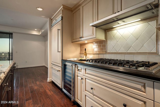 kitchen featuring dark wood-type flooring, paneled refrigerator, stainless steel gas cooktop, wine cooler, and decorative backsplash