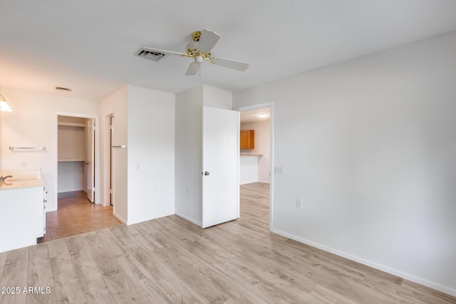 interior space with sink, ceiling fan, a spacious closet, light hardwood / wood-style floors, and a closet