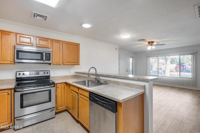 kitchen with kitchen peninsula, appliances with stainless steel finishes, ornamental molding, and sink