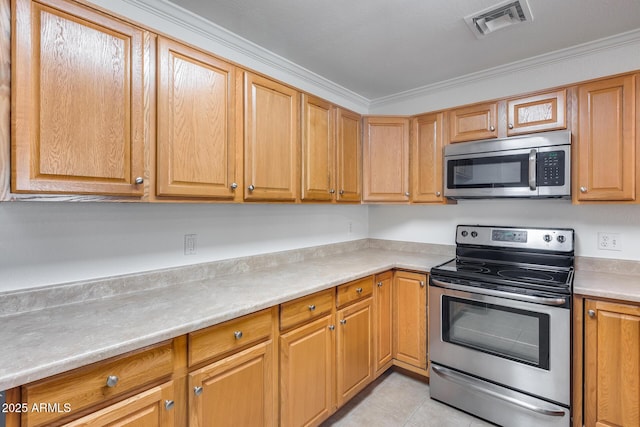 kitchen with light tile patterned floors, stainless steel appliances, and ornamental molding