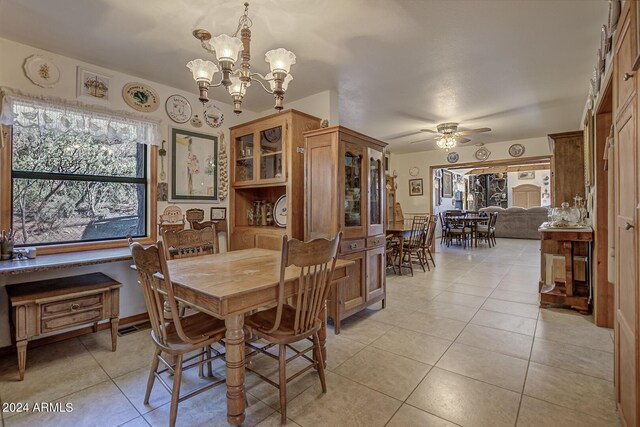 dining space with ceiling fan with notable chandelier and light tile patterned floors