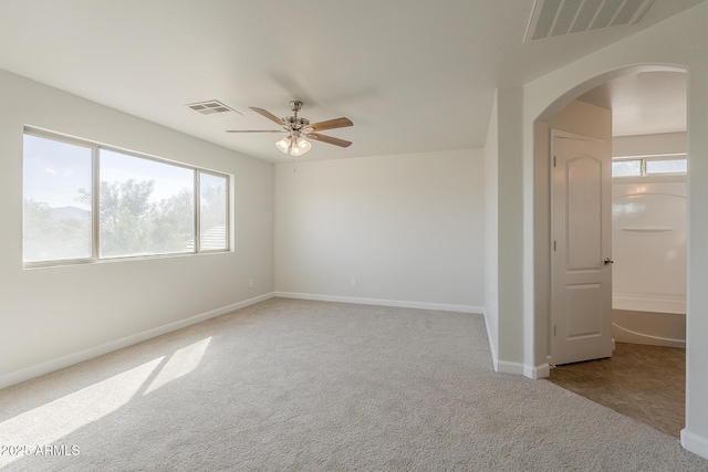 unfurnished room with arched walkways, visible vents, baseboards, and carpet floors