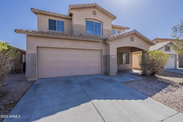 mediterranean / spanish home featuring stucco siding, an attached garage, driveway, and a tiled roof