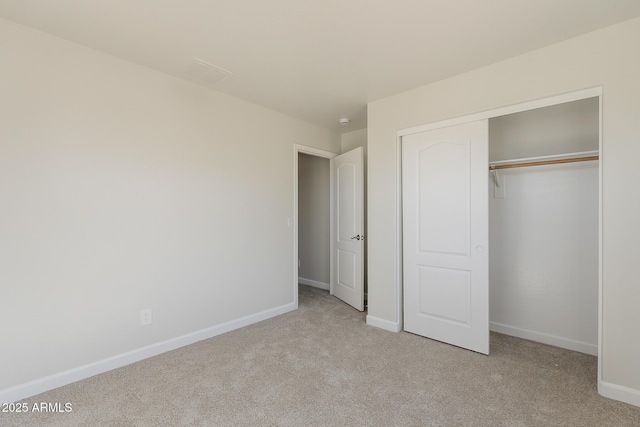 unfurnished bedroom with light colored carpet, baseboards, and a closet